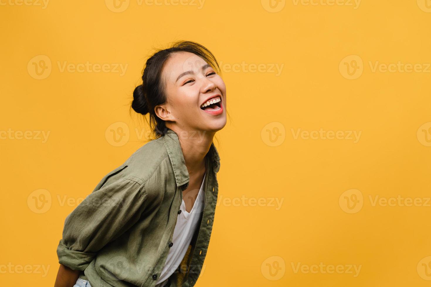 portret van jonge Aziatische dame met positieve uitdrukking, breed glimlachen, gekleed in casual kleding op gele achtergrond. gelukkige schattige blije vrouw verheugt zich over succes. gezichtsuitdrukking concept. foto