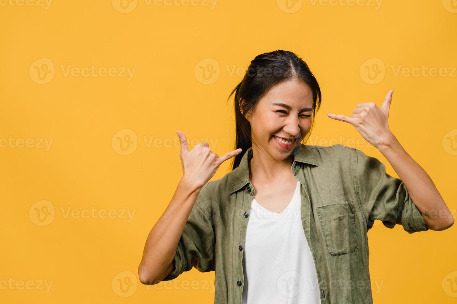 jonge azië dame met positieve uitdrukking, breed glimlachen, gekleed in casual kleding en camera kijken over gele achtergrond. gelukkige schattige blije vrouw verheugt zich over succes. gezichtsuitdrukking concept. foto