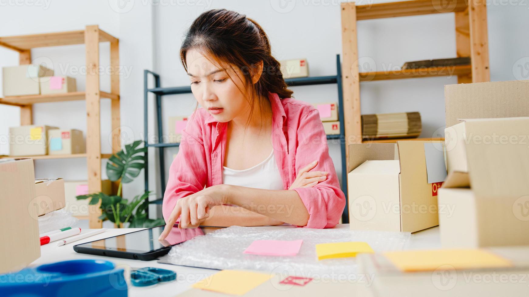 jonge azië ondernemer zakenvrouw check product inkooporder op voorraad en opslaan op tablet computer werk thuis kantoor. eigenaar van een klein bedrijf, online marktlevering, lifestyle freelance concept. foto