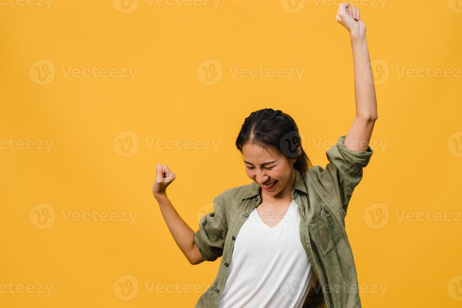 jonge aziatische dame met positieve uitdrukking, vrolijk en opwindend, gekleed in casual doek over gele achtergrond met lege ruimte. gelukkige schattige blije vrouw verheugt zich over succes. gezichtsuitdrukking concept. foto