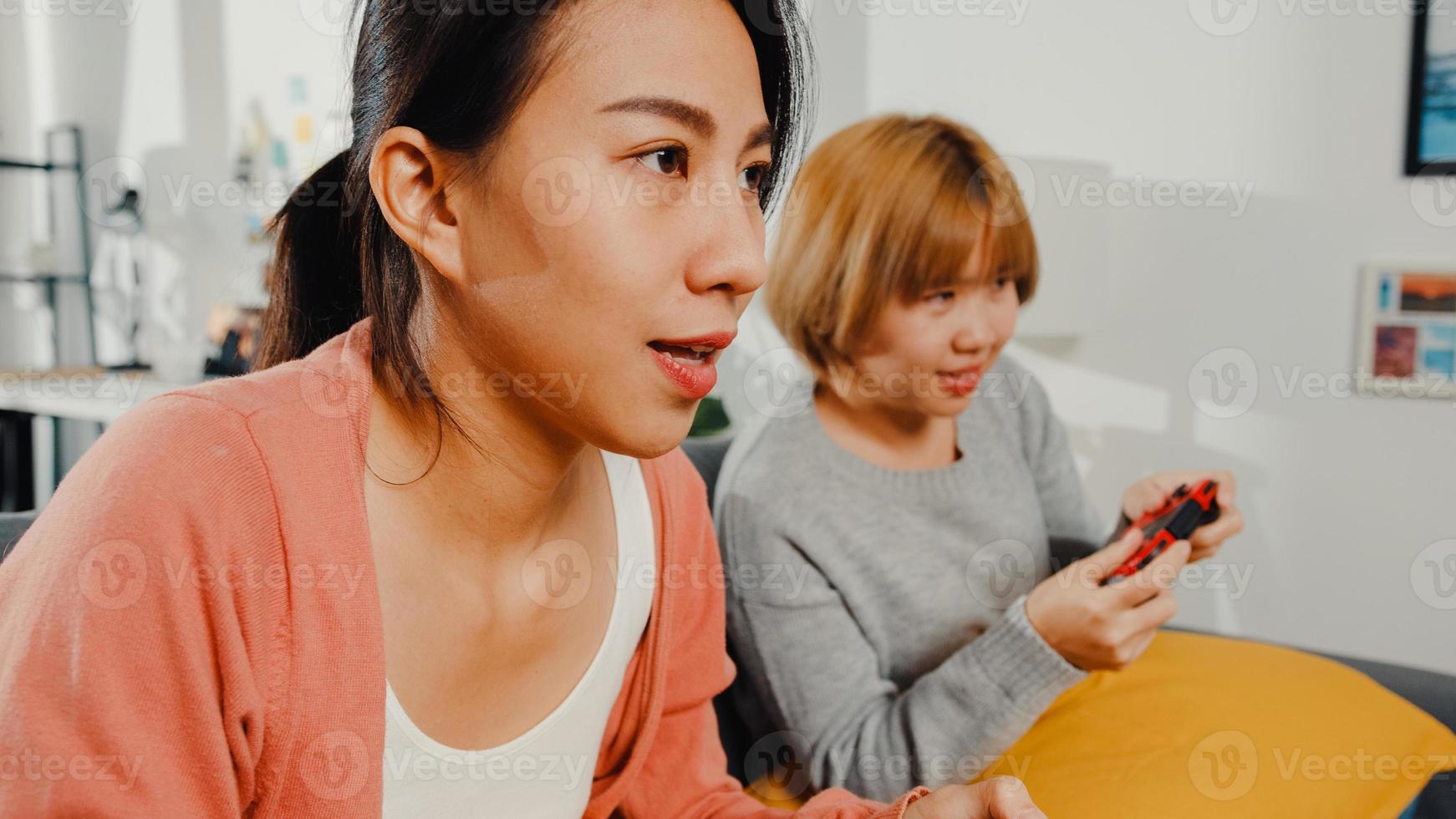 lesbische lgbtq-vrouwen spelen thuis een videogame. jonge Aziatische dame met behulp van draadloze controller met grappig gelukkig moment samen op de bank in de woonkamer. ze hebben een geweldige en leuke tijd om vakantie te vieren. foto