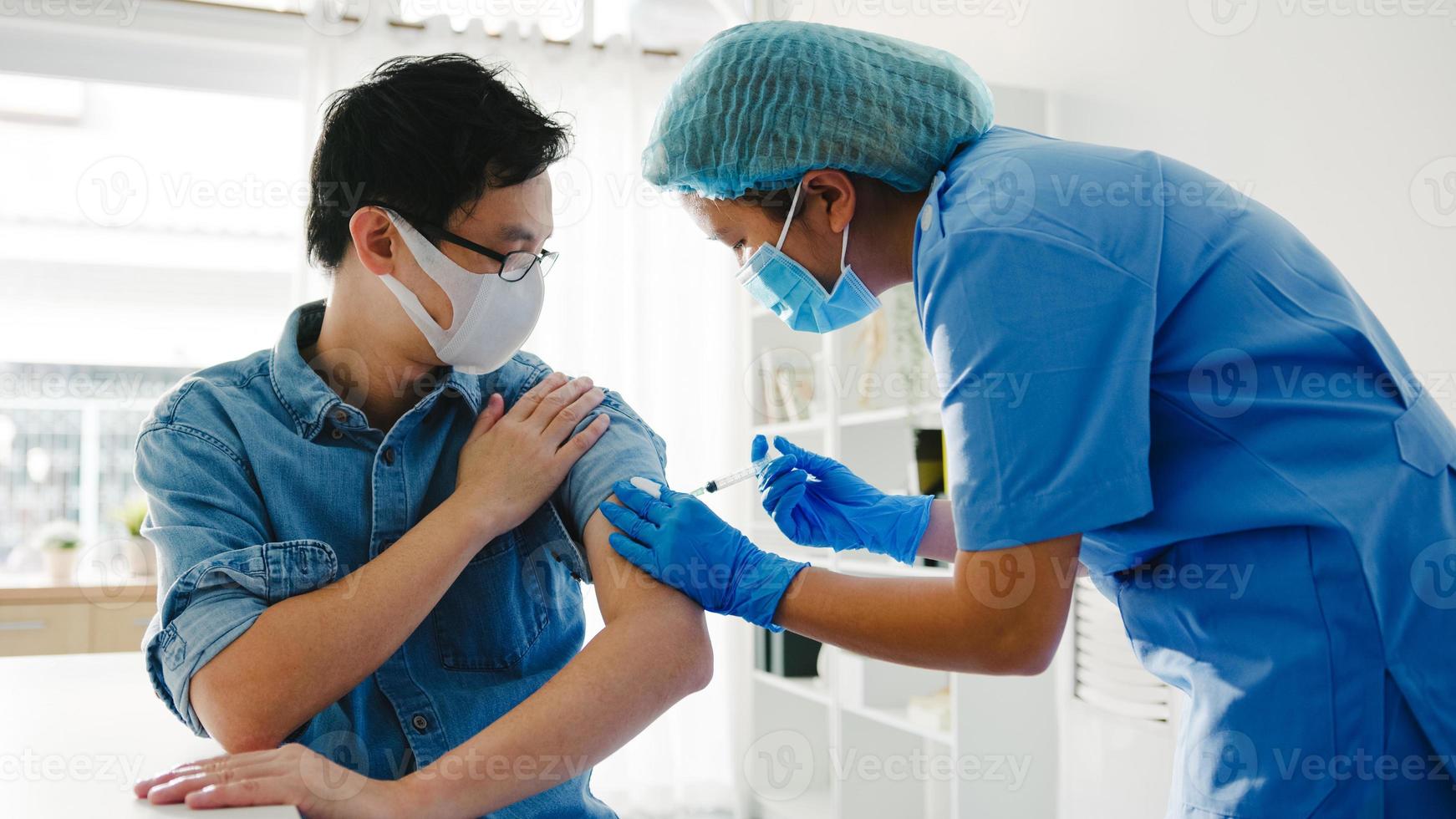 jonge Aziatische vrouwelijke verpleegster die covid-19 of griep-antivirusvaccin geeft aan senior mannelijke patiënt, draag gezichtsmaskerbescherming tegen virusziekte bij gezondheidskliniek of ziekenhuiskantoor. vaccinatie concept. foto
