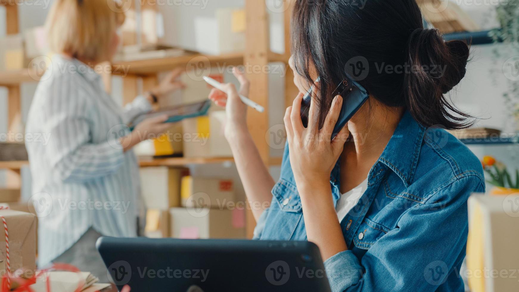 jonge Aziatische zakenvrouwen die mobiel bellen en een inkooporder ontvangen en het product op voorraad controleren op het thuiskantoor. eigenaar van een klein bedrijf, online marktlevering, lifestyle freelance concept. foto