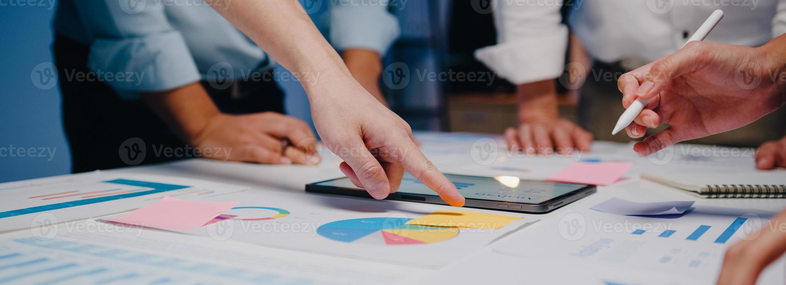 Azië zakenlieden en zakenvrouwen ontmoeten brainstormen ideeën collega's die samenwerken bij het plannen van successtrategie genieten van teamwork in nachtkantoor. panoramische bannerachtergrond met exemplaarruimte. foto