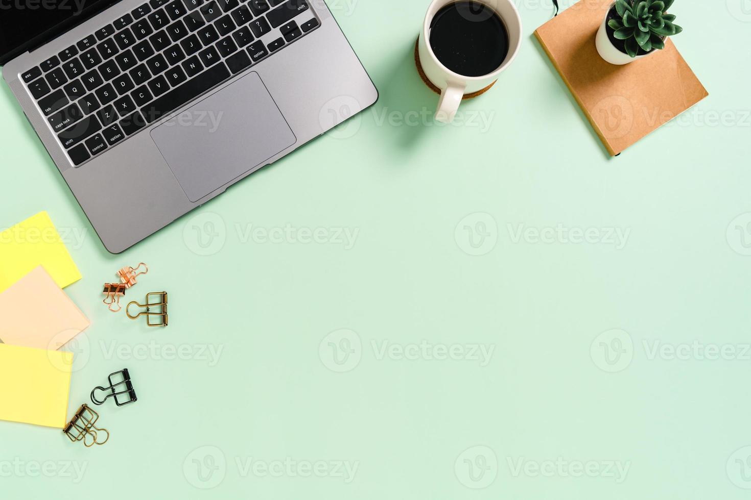 minimale werkruimte - creatieve platliggende foto van werkruimtebureau. bovenaanzicht bureau met laptop en koffiekopje op pastel groene kleur achtergrond. bovenaanzicht met kopieerruimte, platliggende fotografie.