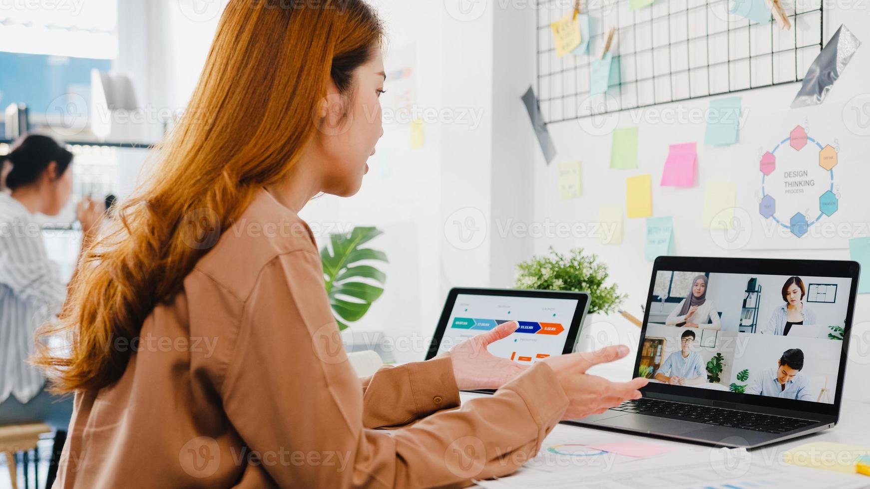 Aziatische zakenmensen die laptop gebruiken, praten met collega's die zakelijke brainstorm bespreken over het plan in een videogesprekvergadering in een nieuw normaal kantoor. levensstijl sociale afstand en werk na het coronavirus. foto