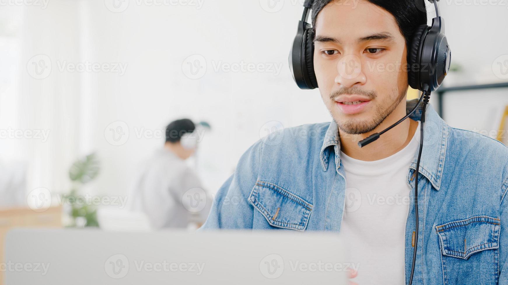 azië zakenman sociale afstand in nieuwe normale situatie voor viruspreventie met behulp van laptoppresentatie aan collega over plan in videogesprek tijdens het werk in een thuiskantoor. levensstijl na het coronavirus. foto