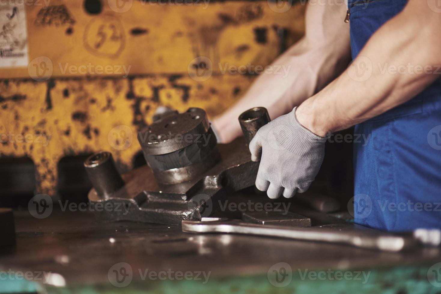 sterke handen houden het stalen deel vast. in de oude fabriek. foto