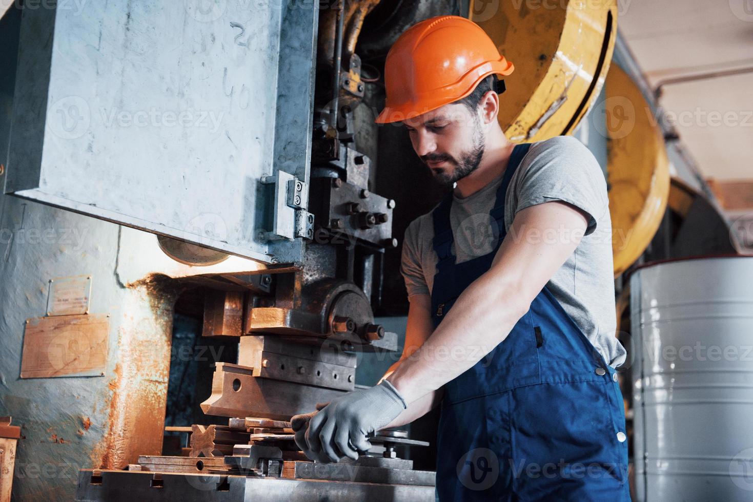 portret van een jonge arbeider met een helm in een grote metaalbewerkingsfabriek. de ingenieur bedient de machines en maakt onderdelen voor gasapparatuur foto