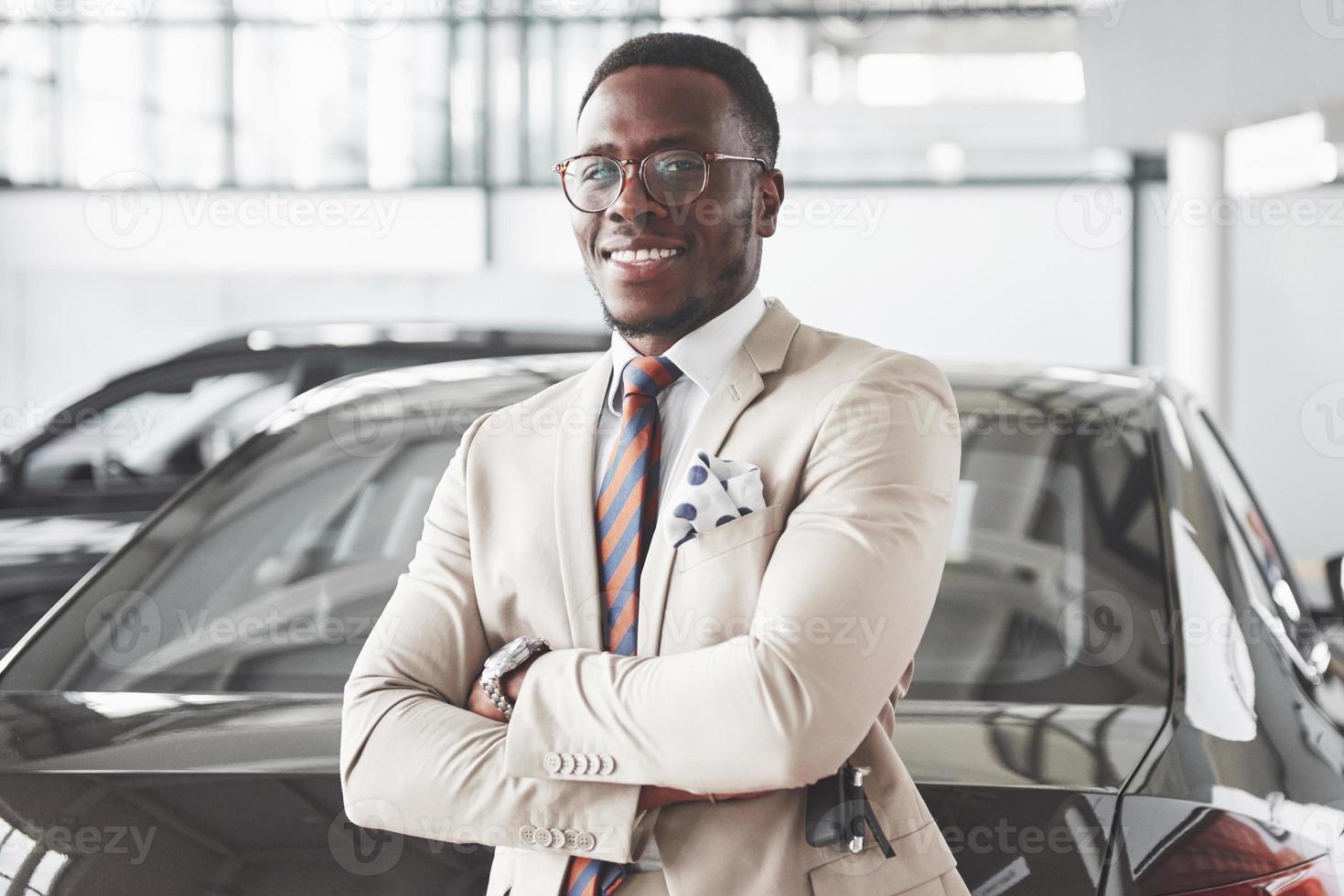 jonge zwarte zakenman op auto salon achtergrond. auto verkoop en verhuur concept foto