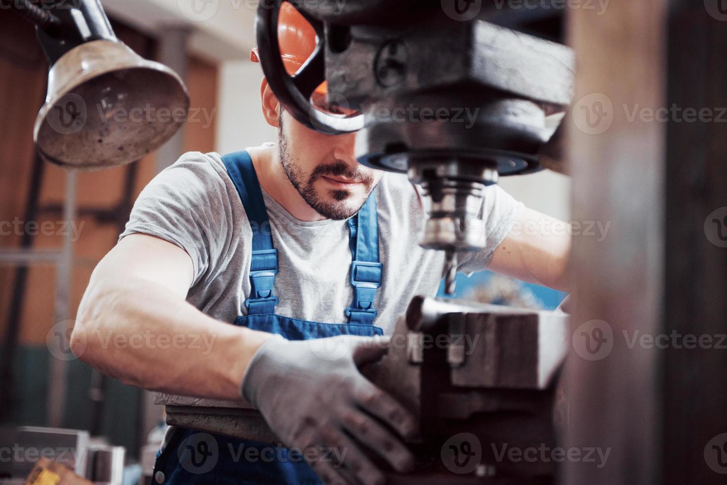 portret van een jonge arbeider met een helm in een grote metaalbewerkingsfabriek. de ingenieur bedient de machines en maakt onderdelen voor gasapparatuur foto