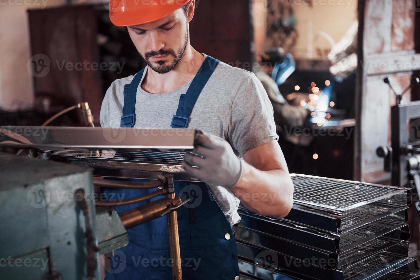 portret van een jonge werknemer met een helm in een grote afvalrecyclingfabriek. de ingenieur bewaakt het werk van machines en andere apparatuur; foto