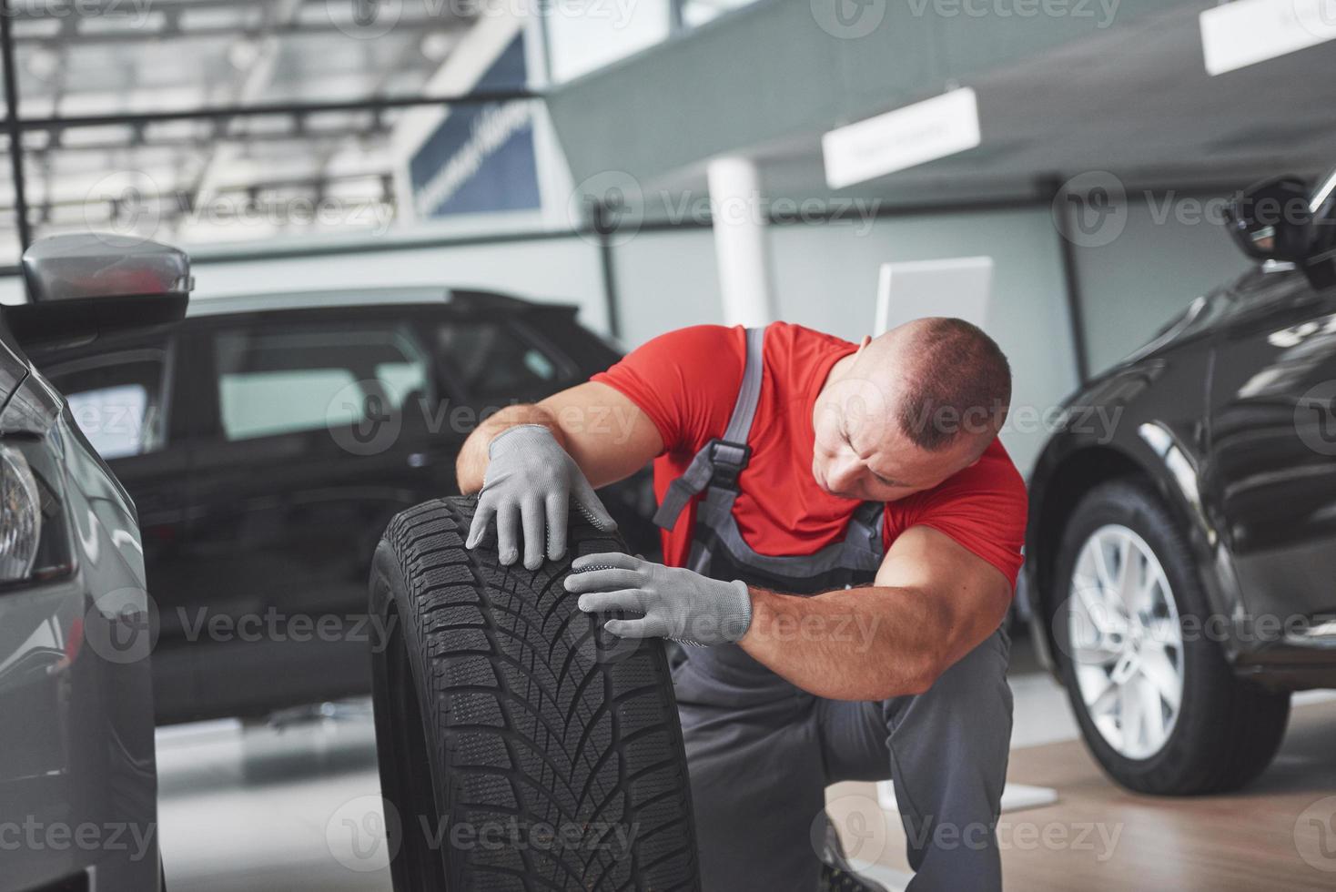 monteur die een bandband vasthoudt bij de reparatiegarage. vervanging van winter- en zomerbanden foto