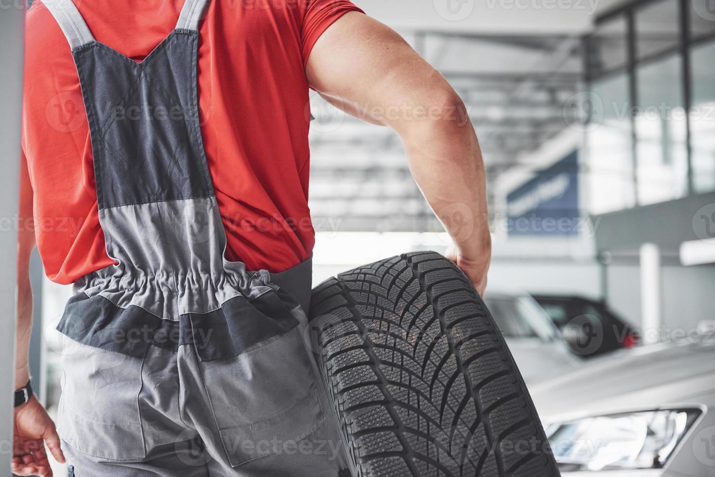 monteur die een bandband vasthoudt bij de reparatiegarage. vervanging van winter- en zomerbanden foto