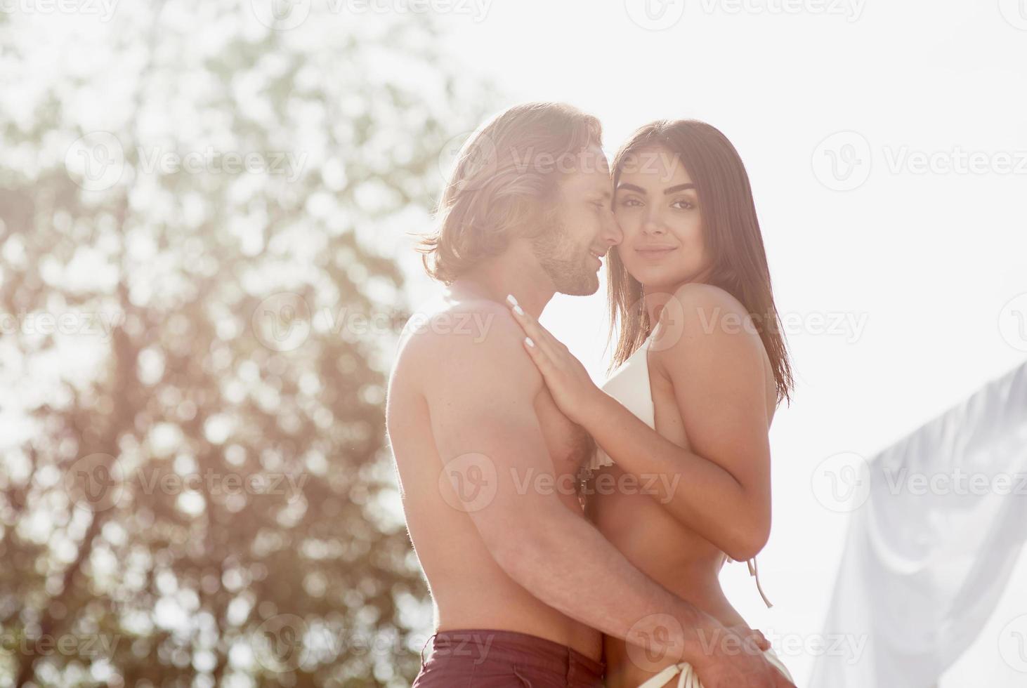 mooie sexy paar jongen en meisje dragen badkleding op het strand. romantisch liggend op het zand foto