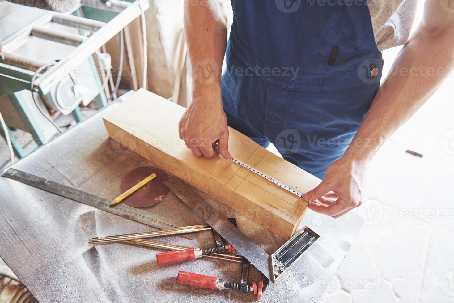 een man werkt in een schrijnwerkerij, aan het werk met een boom. foto