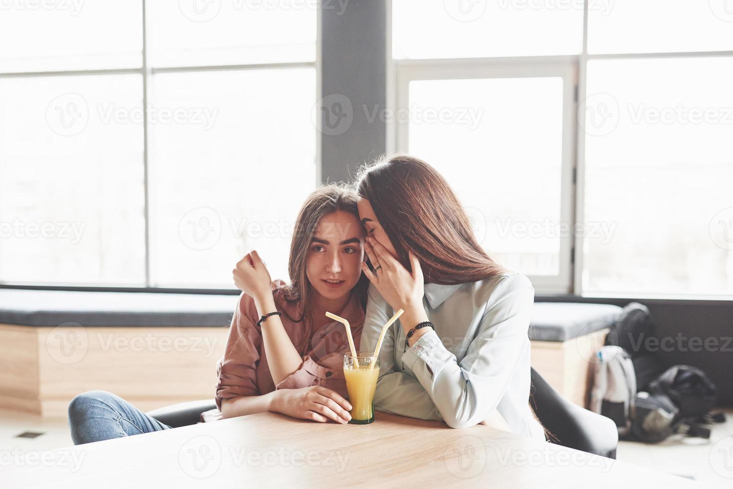 twee mooie tweelingmeisjes brengen tijd door met het drinken van sap. zussen ontspannen in een café en samen plezier maken foto