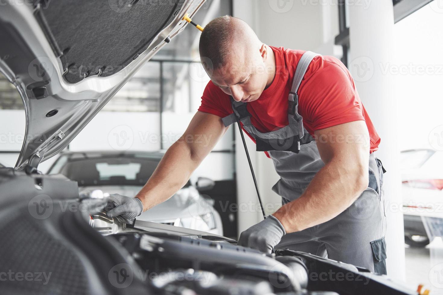 foto van gespierde autoservicemedewerker die voertuig repareert