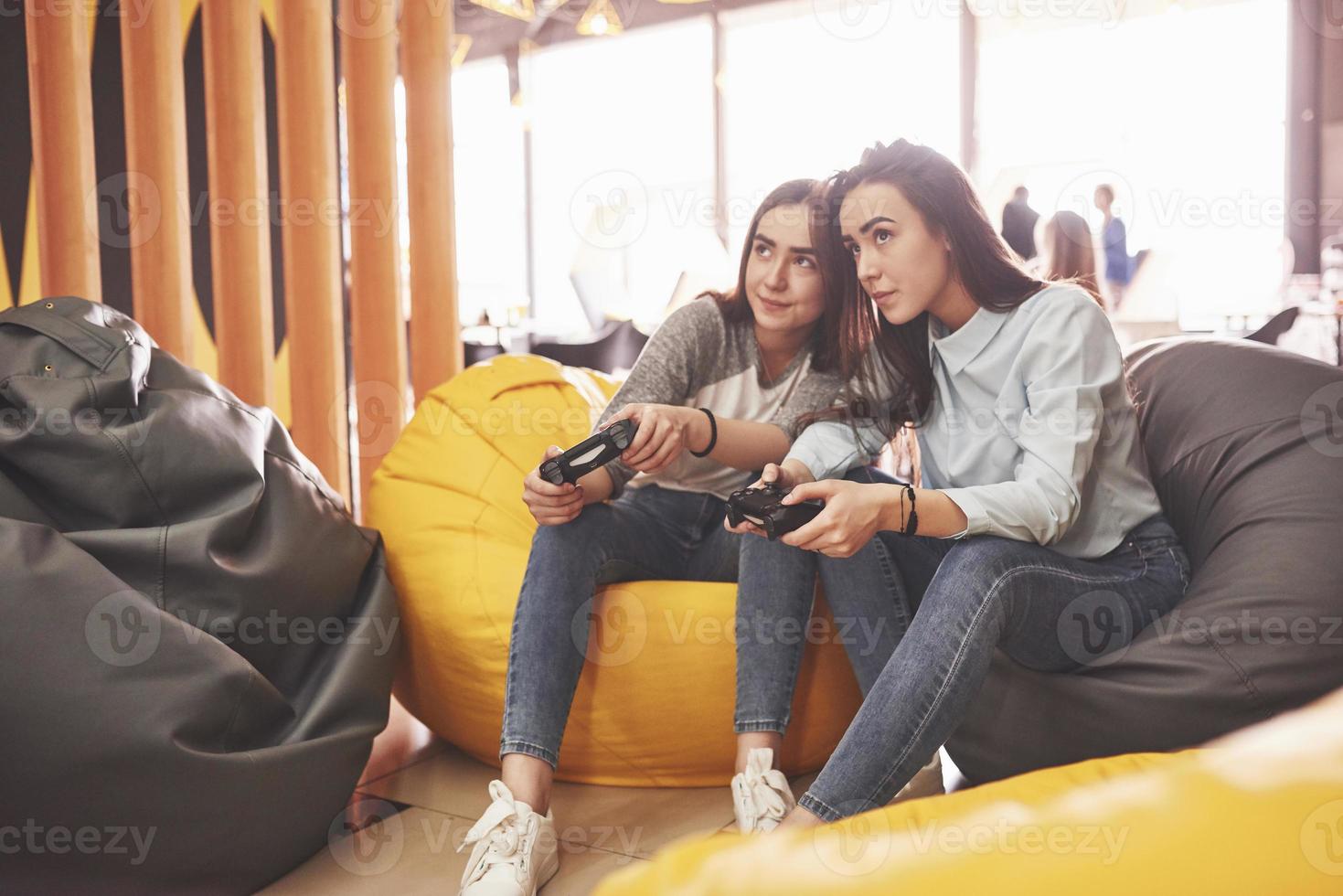 tweelingzusjes spelen op de console. meisjes houden joysticks in hun handen en hebben plezier foto