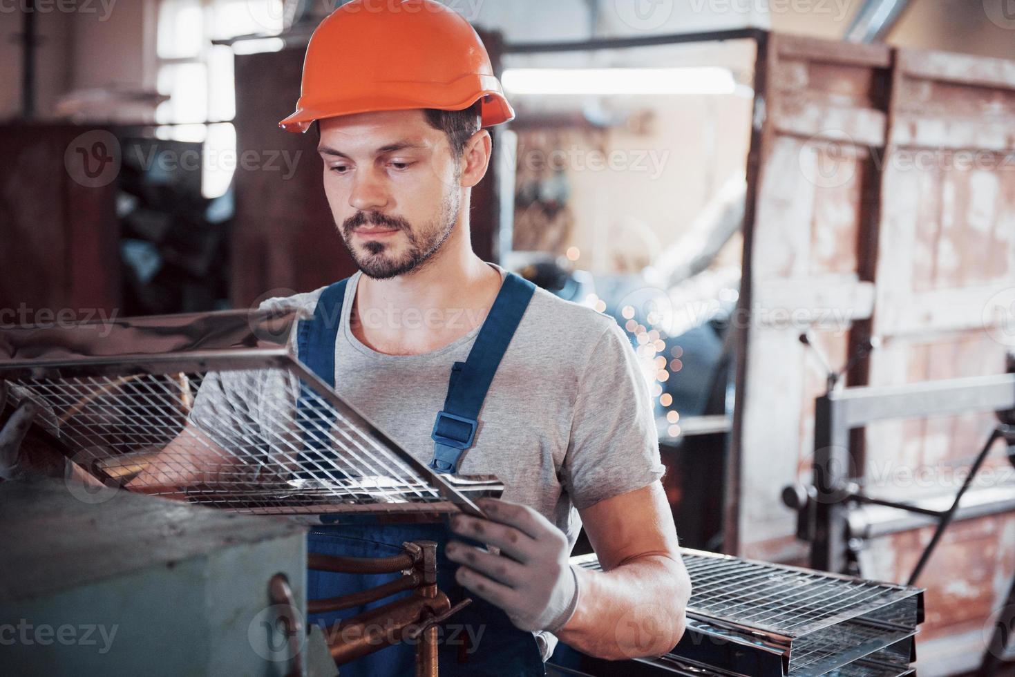 portret van een jonge werknemer met een helm in een grote afvalrecyclingfabriek. de ingenieur bewaakt het werk van machines en andere apparatuur; foto