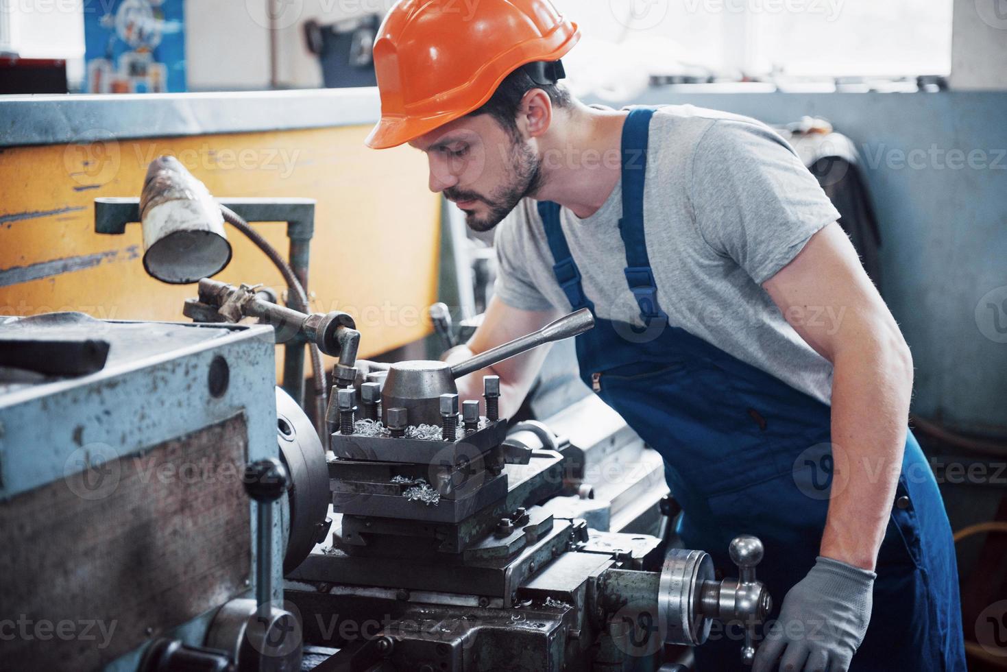 portret van een jonge werknemer met een helm in een grote afvalrecyclingfabriek. de ingenieur bewaakt het werk van machines en andere apparatuur; foto