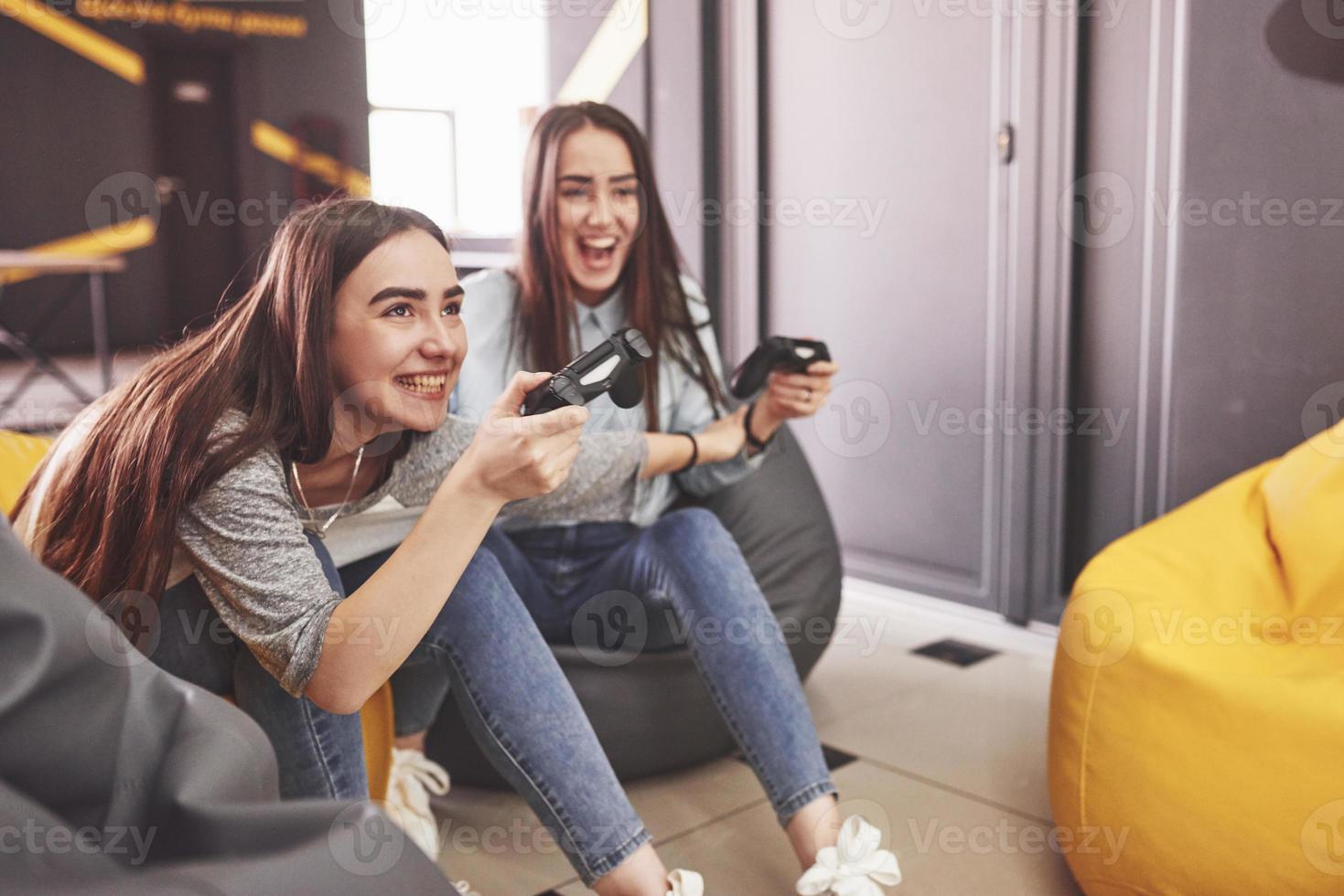 tweelingzusjes spelen op de console. meisjes houden joysticks in hun handen en hebben plezier foto