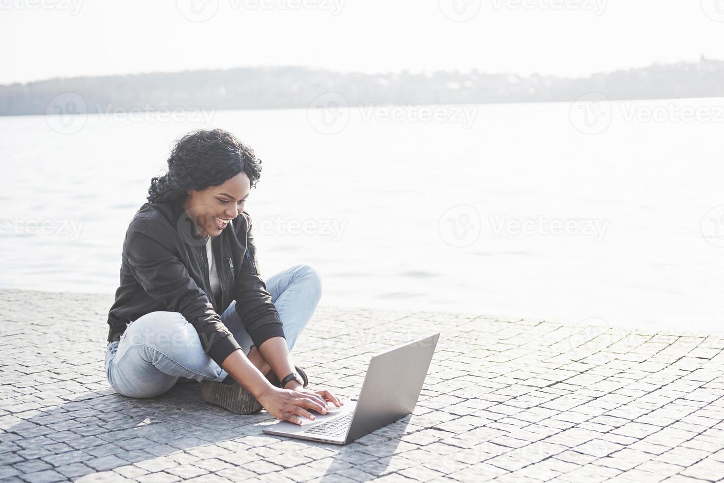 jonge vrouw op straat die aan laptop werkt foto