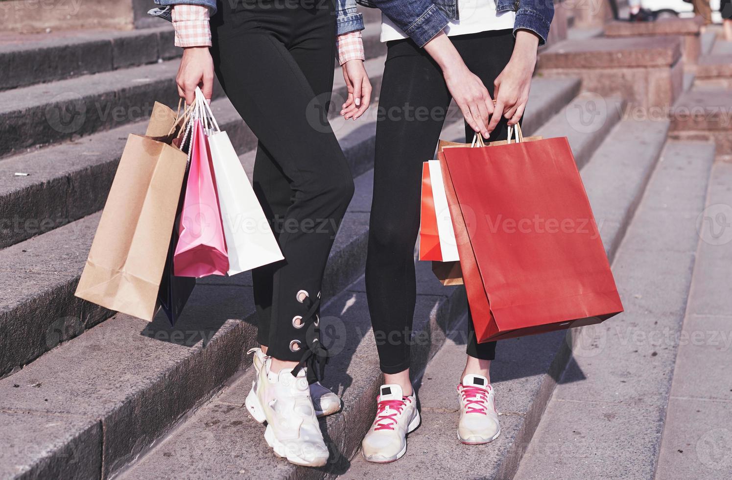 twee jonge vrouw die boodschappentassen draagt terwijl ze over straat loopt na een bezoek aan de winkels foto