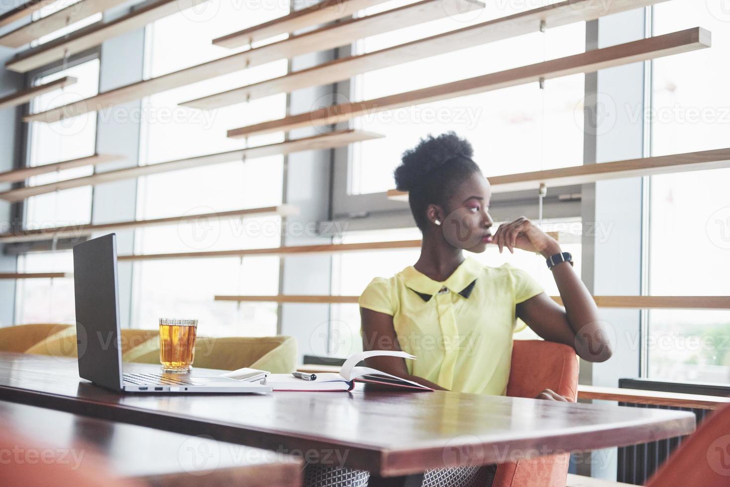 jonge Afro-Amerikaanse meid met donker krullend haar peinzend in een café. foto