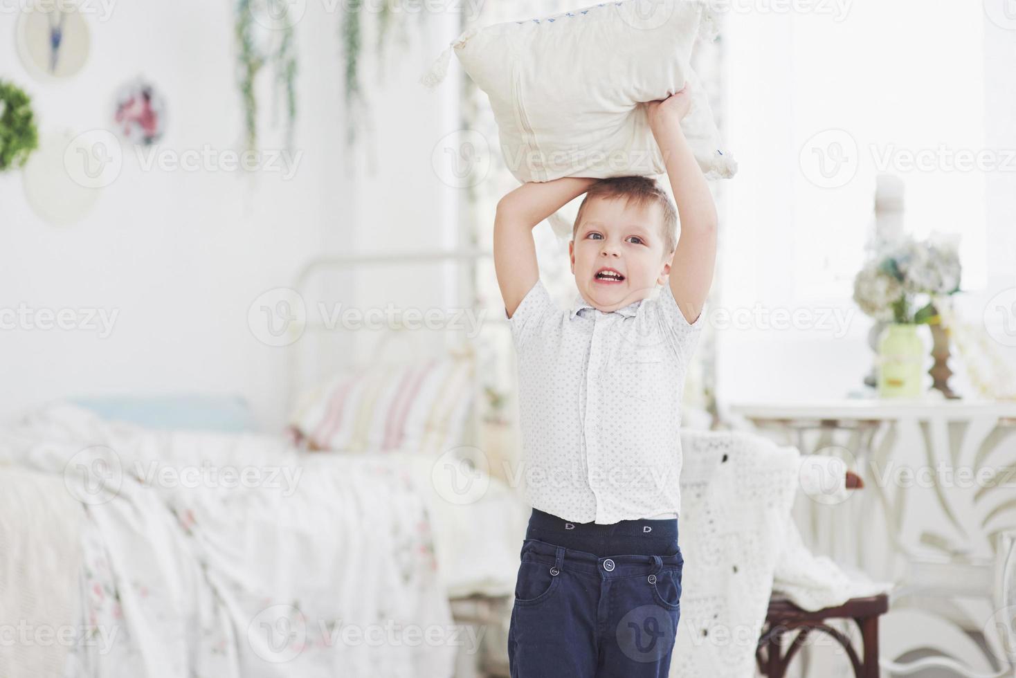 kleine jongen in wit overhemd met kussen. kussengevecht foto