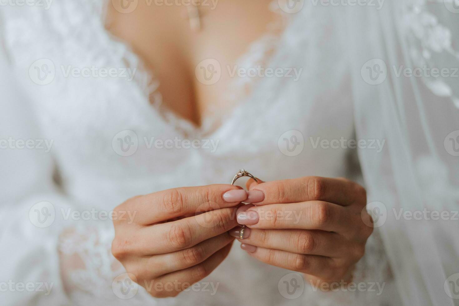 details bruiloft accessoires. de bruid houdt een goud bruiloft ring met een diamant in haar handen, bijgesneden foto. mooi handen. Open buste foto