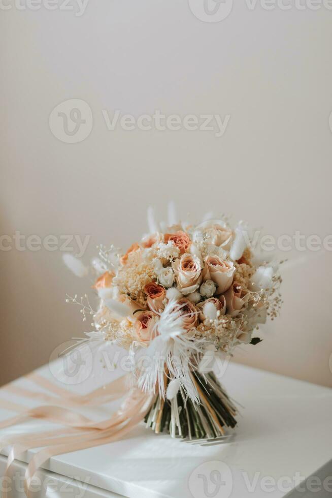 bruiloft boeket van roze rozen, veren en droog bloemen Aan een houten staan foto