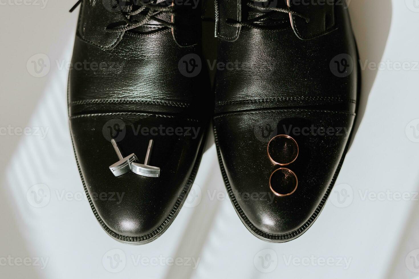 details van de bruidegom Aan de wit vloer. zwart leer Mannen schoenen, goud bruiloft ringen, manchetknopen foto
