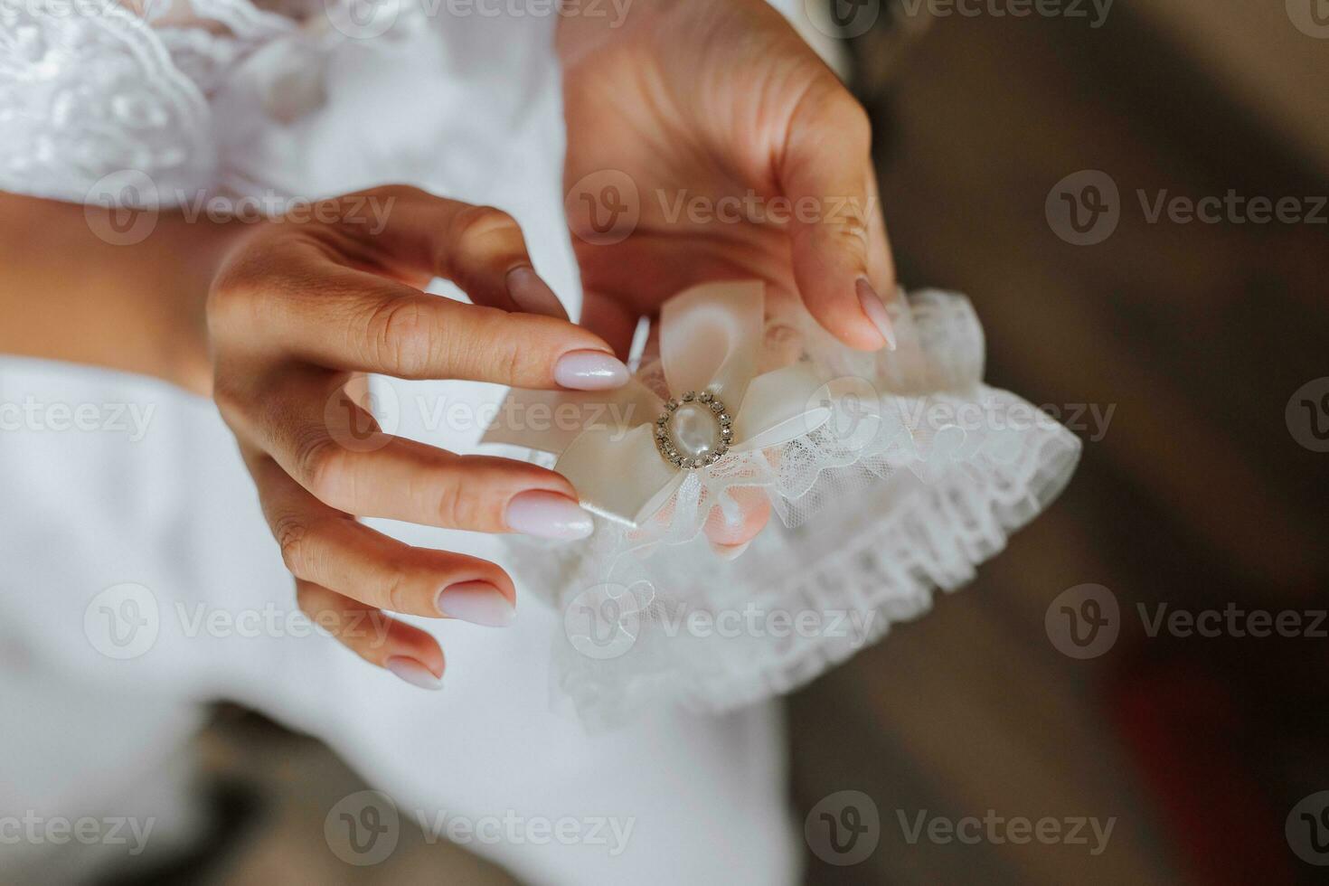 kousenband Aan de been van de bruid in haar handen, detailopname. ochtend- van de bruid foto