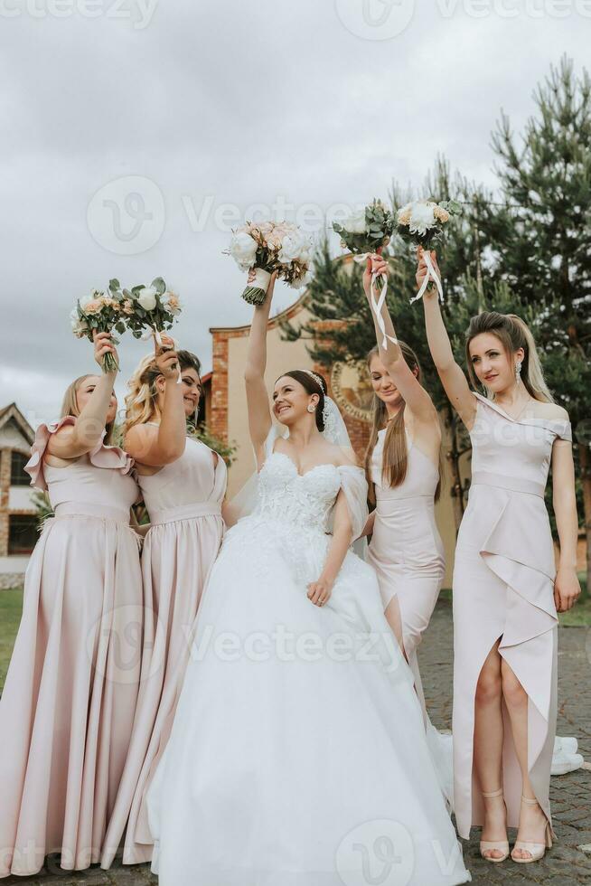 groep portret van de bruid en bruidsmeisjes hebben plezier. bruiloft. een bruid in een bruiloft jurk en haar vrienden in roze jurken Aan de bruiloft dag. elegant bruiloft in poeder kleur. concept van huwelijk. foto