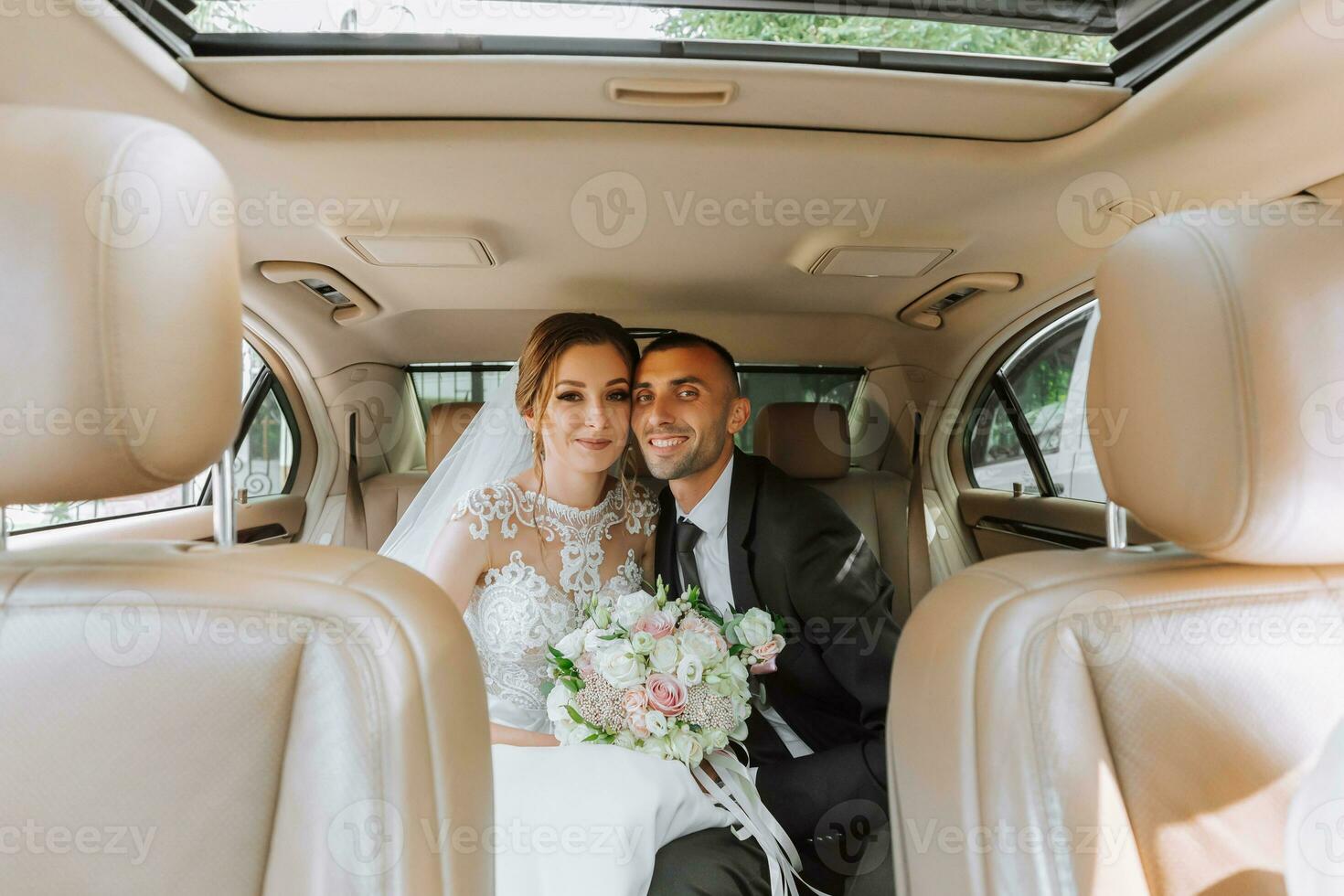 jong gelukkig bruid en bruidegom zijn verheugt na de bruiloft ceremonie in hun auto foto