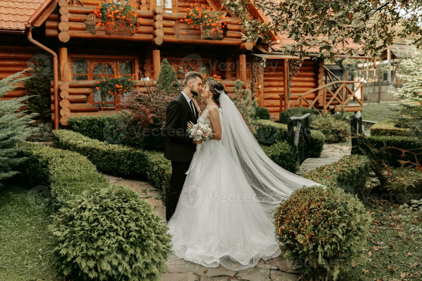 prachtig elegant luxueus bruid met sluier blazen in de wind. en een elegant bruidegom kus buitenshuis in de buurt hoog herfst bomen foto