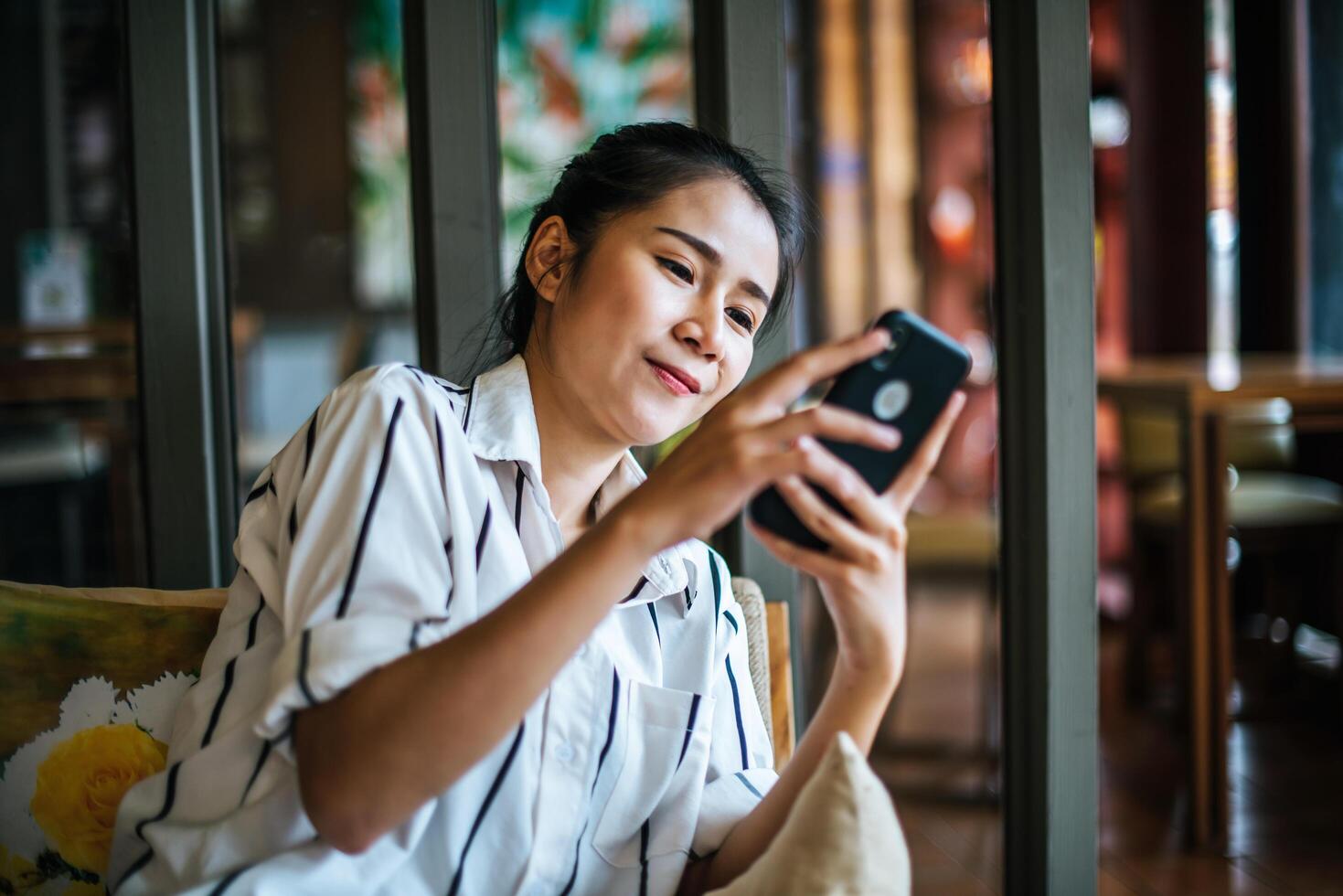 vrouw zit en speelt haar smartphone in café foto