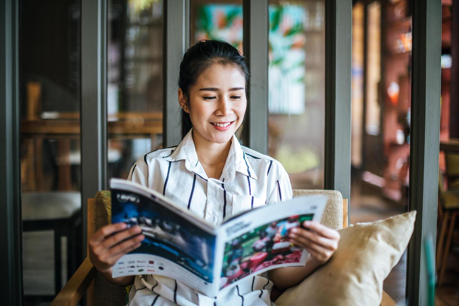 mooie vrouw die tijdschrift leest in café foto