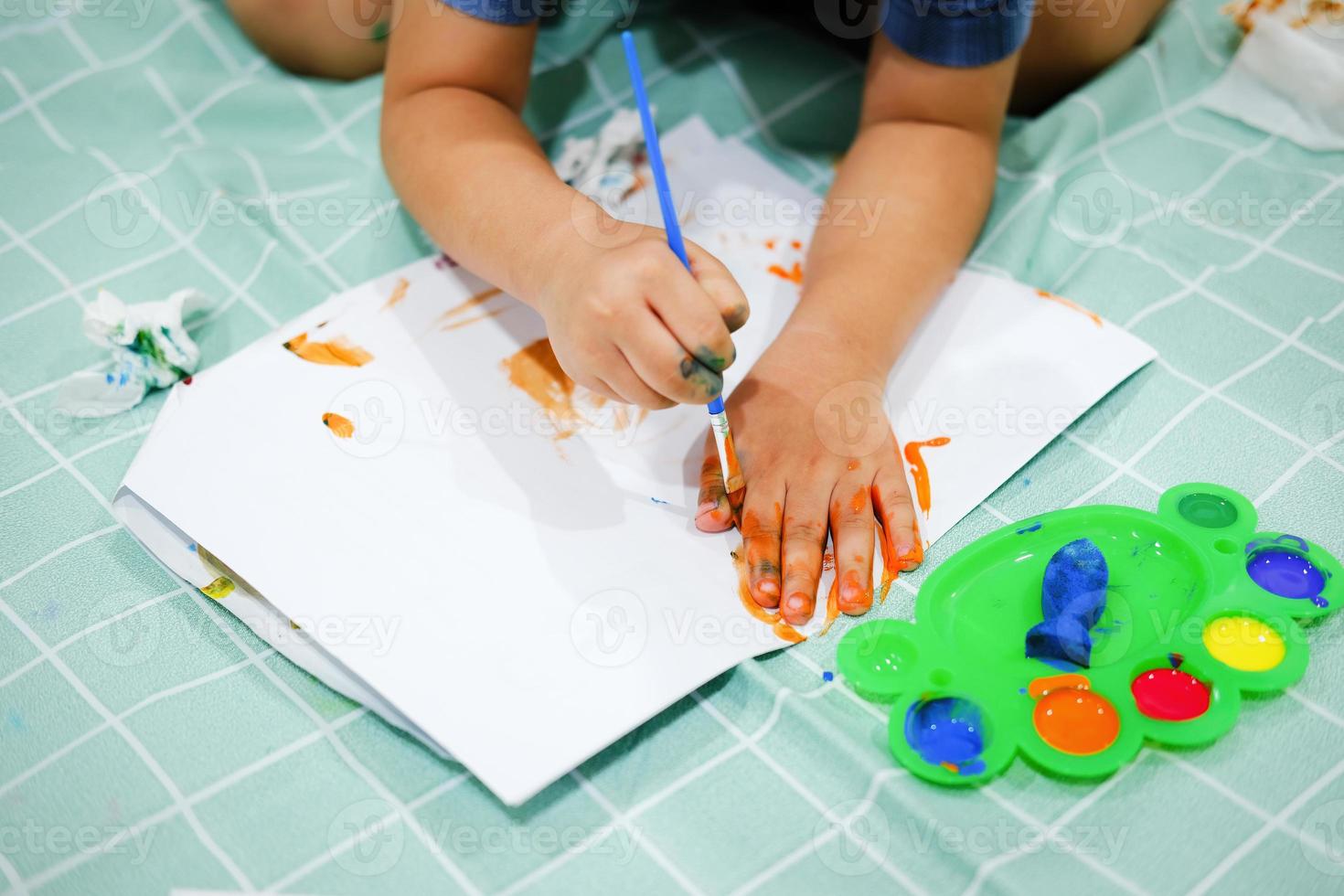 focus op hun handen op papier. kinderen gebruiken penselen om hun handen op papier te tekenen om hun verbeeldingskracht op te bouwen en hun cognitieve vaardigheden te verbeteren. foto