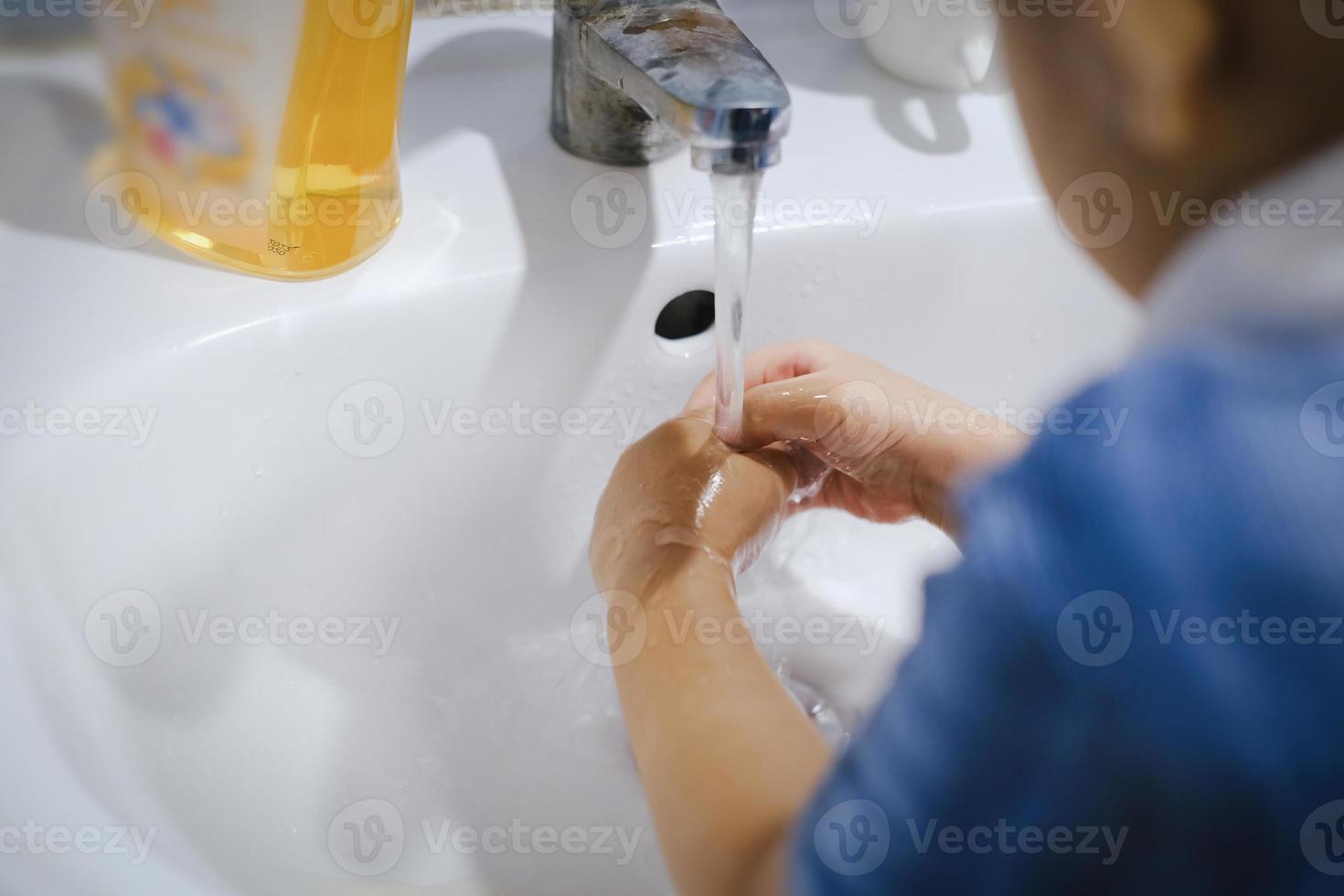 kleine jongen die zijn handen wast met zeep om de ziektekiemen van het coronavirus te verwijderen. foto