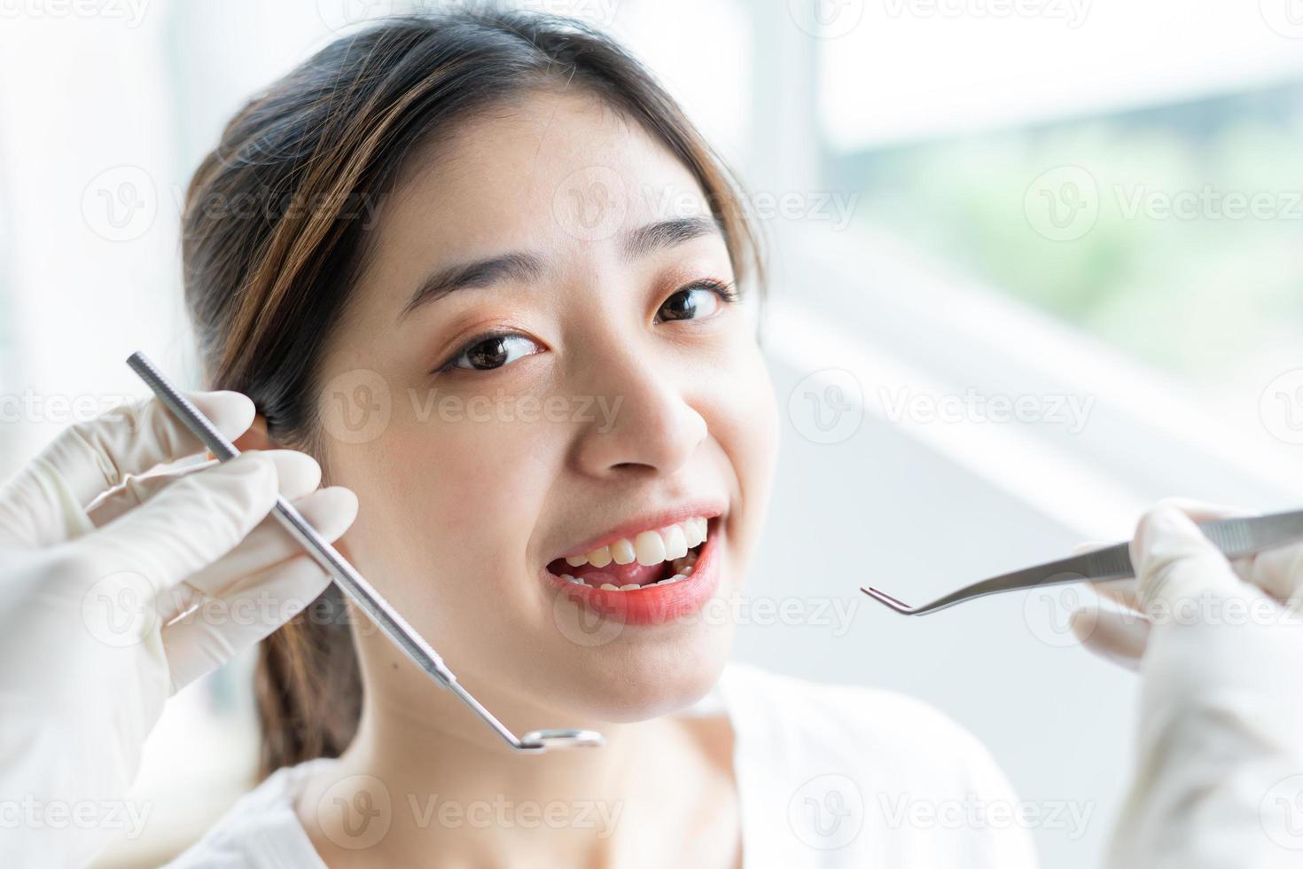 portret van een jonge blanke vrouw met een perfecte glimlach in de tandartspraktijk, kom om verwende tanden te behandelen, kijk naar de camera foto