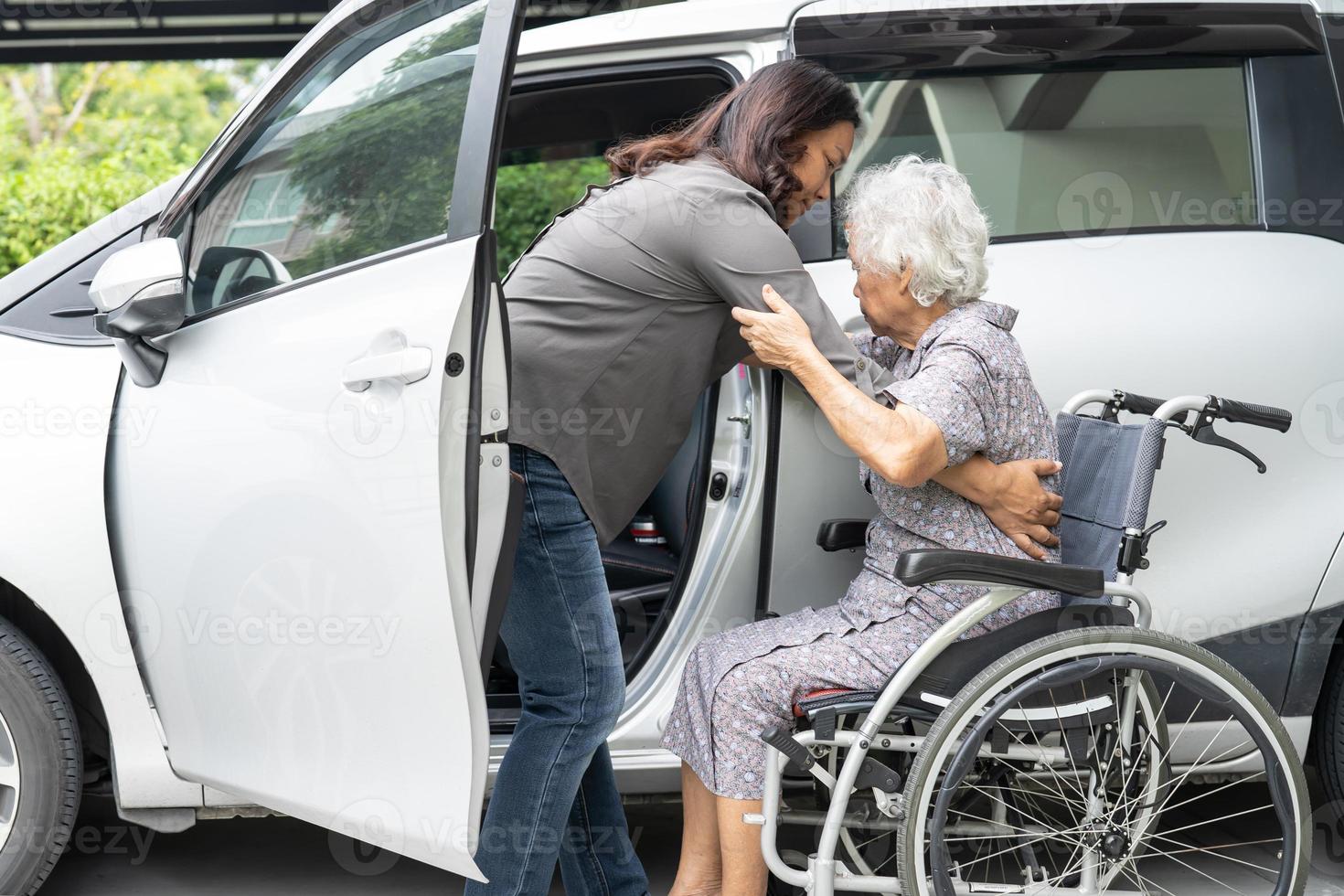 hulp en ondersteuning aziatische senior of oudere oude dame vrouw patiënt zittend op rolstoel voorbereiden om naar haar auto te gaan, gezond sterk medisch concept. foto