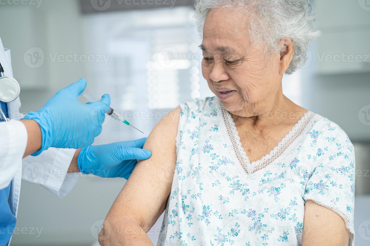 oudere aziatische senior vrouw met gezichtsmasker die covid-19 of coronavirusvaccin krijgt door een arts, maakt injectie. foto