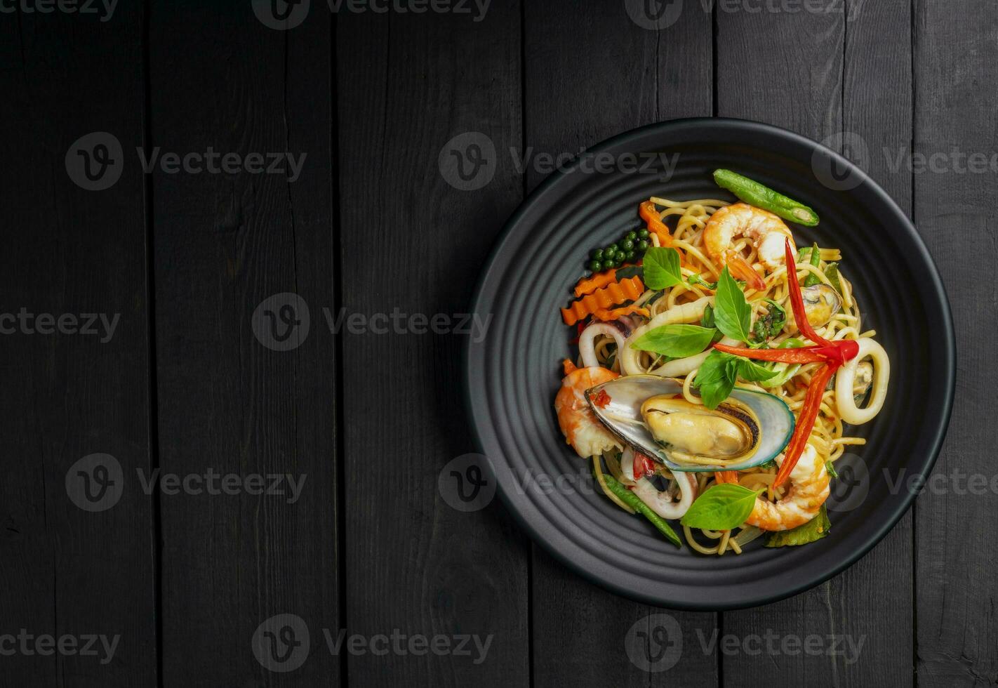 zeevruchten dronken spaghetti met garnaal inktvis mosselen Chili, en basilicum. Thais voedsel. gezond Aziatisch in een bord Aan een zwart achtergrond tafel. top visie. foto
