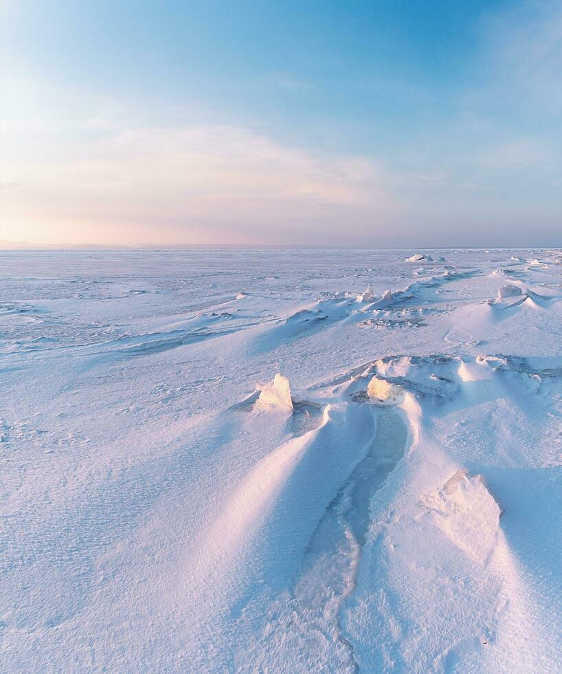 winter landschap. sneeuwbanken Aan de ijs oppervlakte gedurende zonsondergang. foto