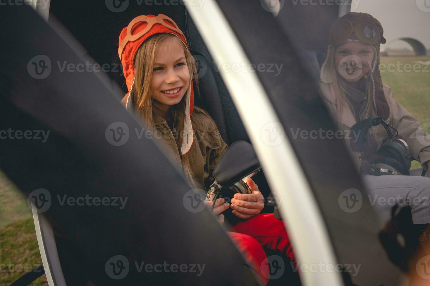 glimlachen tween meisje zittend in kuip van geland helikopter in de buurt vriend foto