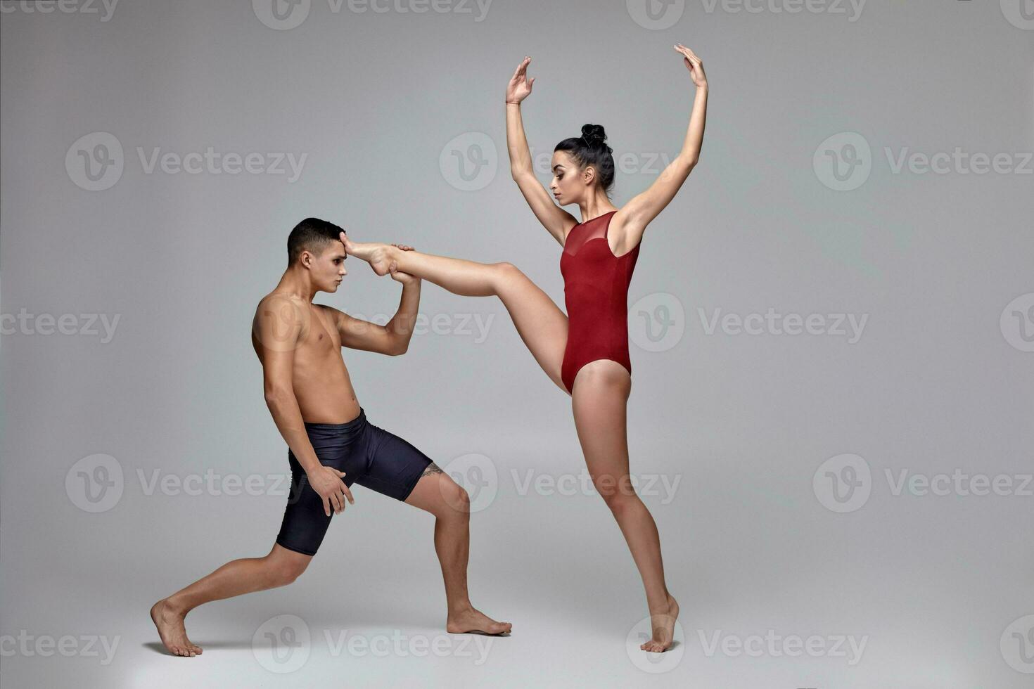 de paar van een atletisch modern ballet dansers zijn poseren tegen een grijs studio achtergrond. foto