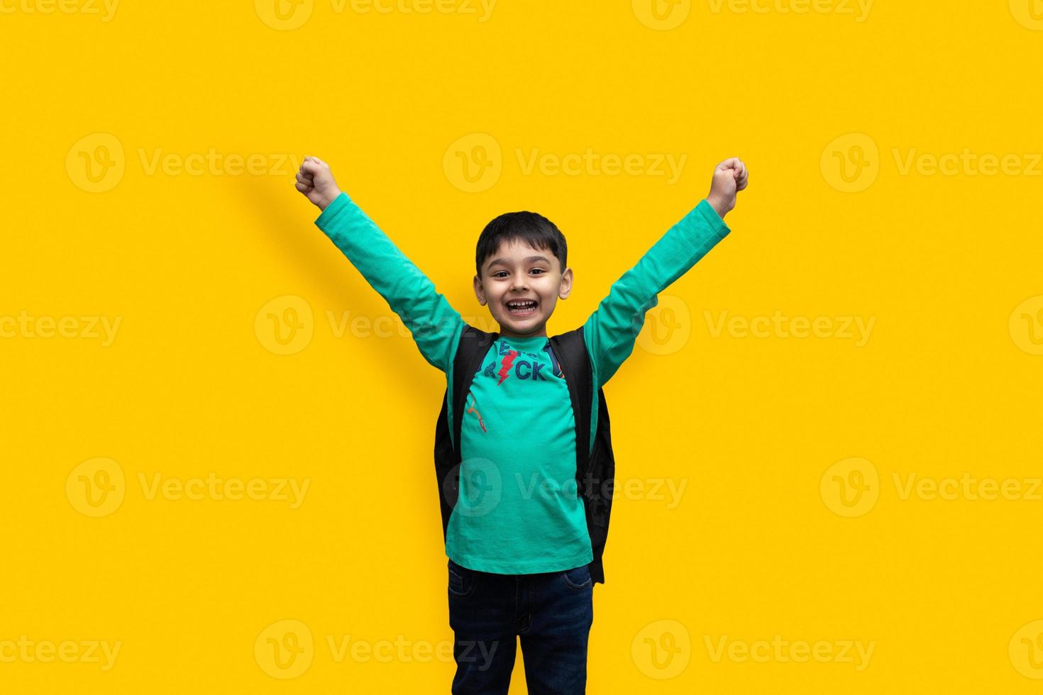 schattige 7-jarige gelukkige jongen met schoolrugzak met boeken op een effen achtergrond voor onderwijsconcept foto