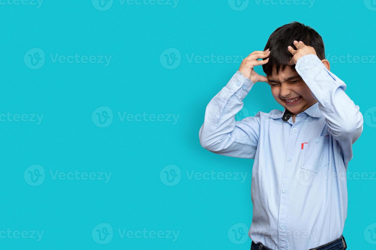 trieste en agressieve kleine zieke jongen die zijn hoofd met zijn hand op een vliegtuig geïsoleerde achtergrond houdt met kopieerruimte foto